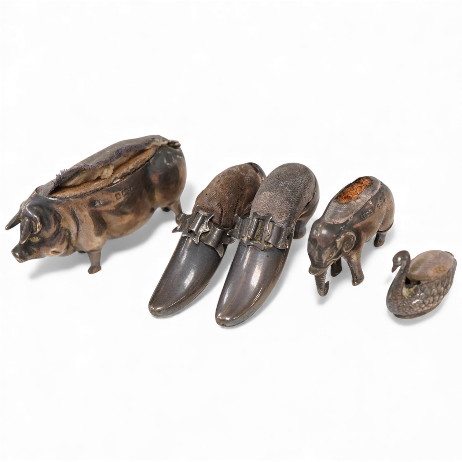 Five assorted novelty silver pin cushions, to include a model pig, maker's mark rubbed, Birmingham, 1903, length 67mm, two model shoes by Adie & Lovekin, a small elephant by Saunders & Shepherd, Birmingham, 1905 and a ti